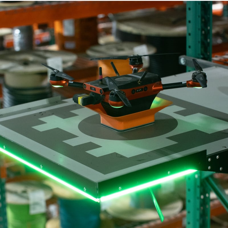A Corvus One warehouse inventory drone recharges on its landing pad.