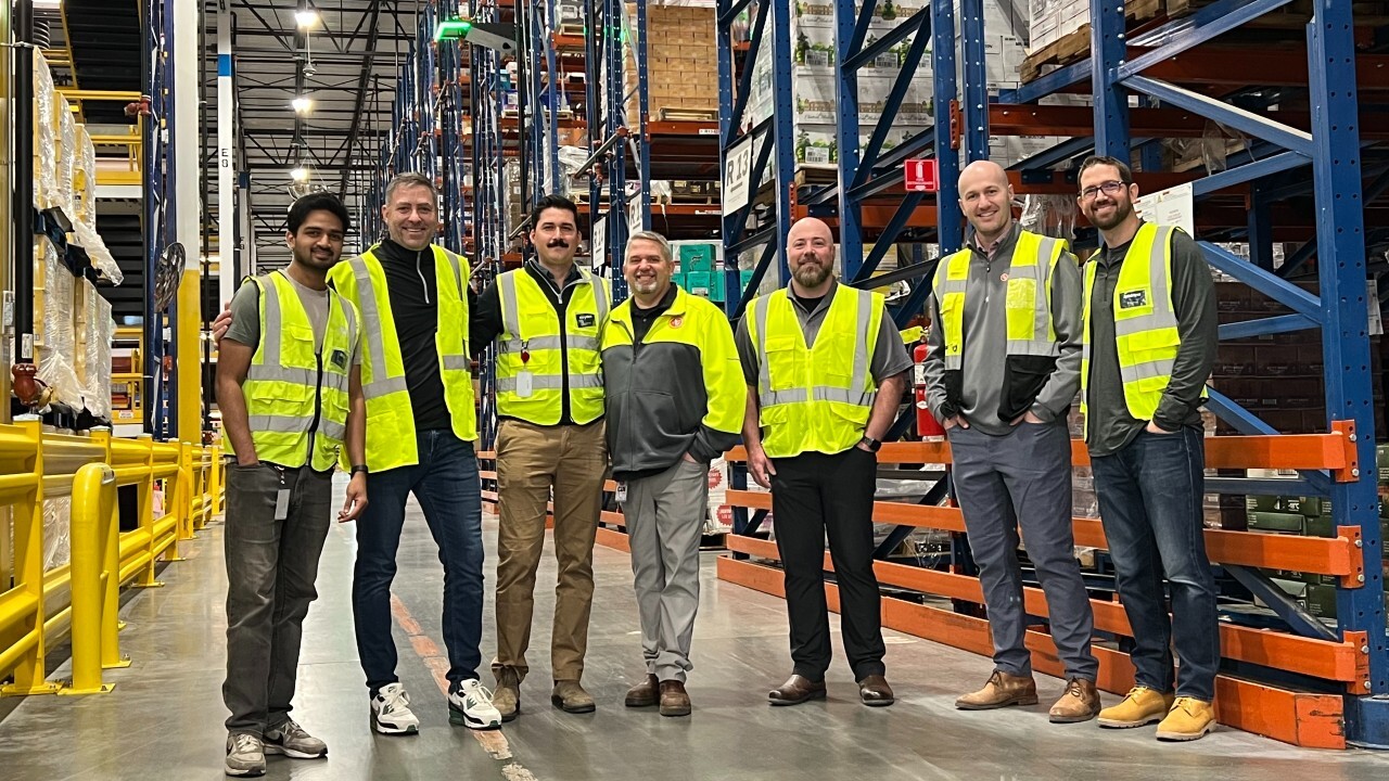 Team members from Corvus Robotics and Southern Glazer's Wine & Spirits pose for a photo in front of high-bay racking and a Corvus One landing pad in Southern Glazer's Raymore, MO distribution Center.