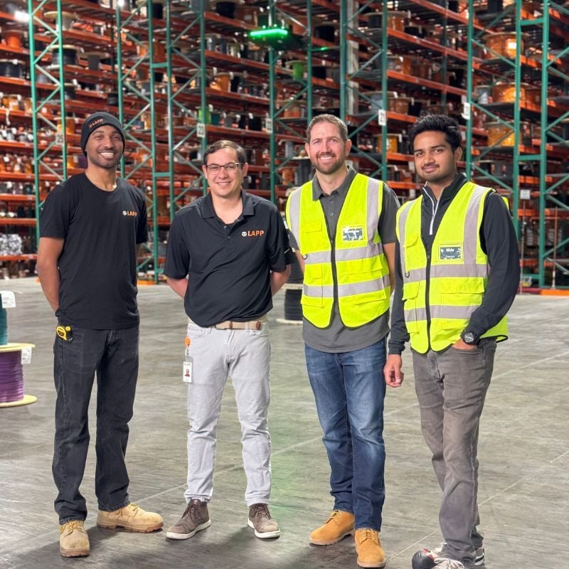 Team members from LAPP USA and Corvus Robotics pose for a photo in front of racks and the Corvus One landing pad at LAPP's Brownsburg, IN facility.