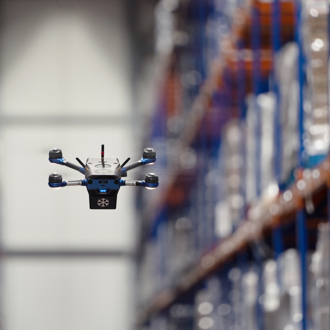 A Corvus One for Cold Chain drone flies between racks while performing inventory counts.